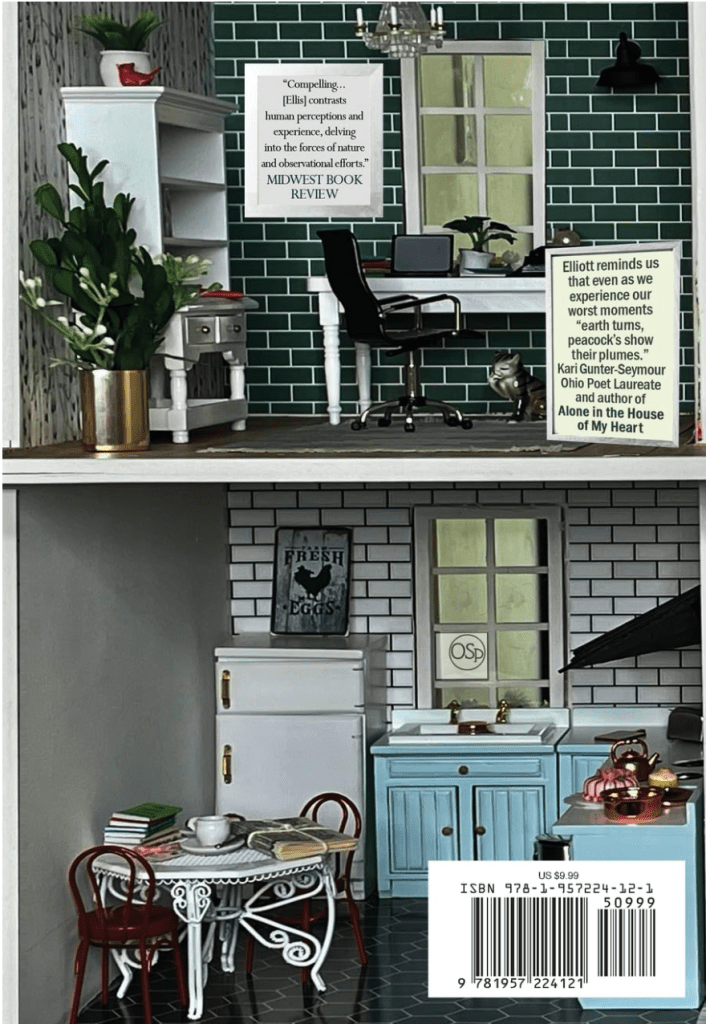 Image of a cozy kitchen and office space with green tiled walls, white appliances, a round dining table with red chairs, and a desk chair near a window.